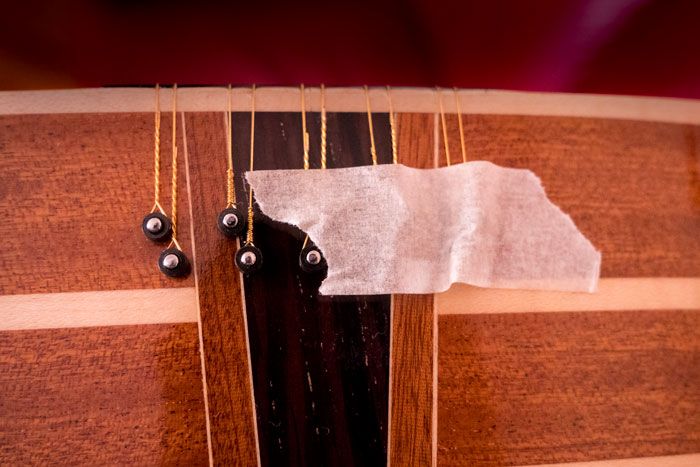 Corde per chitarra battente fissate alla fascia inferiore con nastro di carta per mascheratura per  cambiare le corde alla chitarra battente